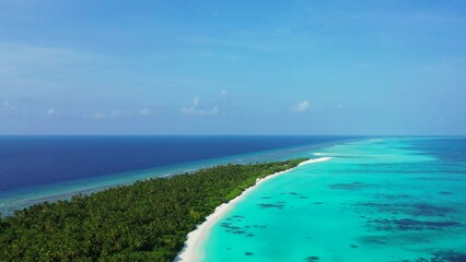 Drone shot of a green island with turquoise and blue water in The Maldives, Asia