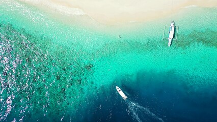 Aerial top view of yachts floating in turquoise water by a beach in the Maldives