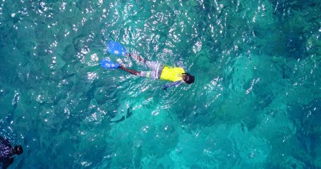 Top view of a man swimming in turquoise water with coral reef in the Maldives