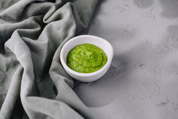 Fresh homemade green pesto sauce in white bowl