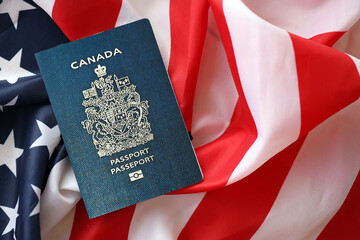 Naklejka premium Canadian passport on United States national flag background close up. Tourism and diplomacy concept