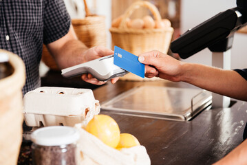 Close-Up View of a Customer Handing Over Credit Card for Payment at Grocery Checkout