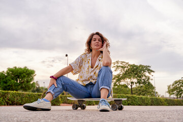 young Caucasian woman sitting on the skateboard - Powered by Adobe