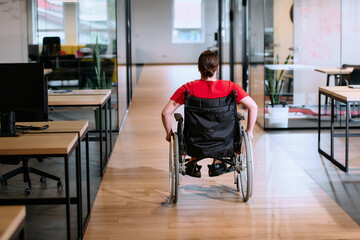 A modern young businesswoman in a wheelchair is surrounded by an inclusive workspace with glass-walled offices, embodying determination and innovation in the business world