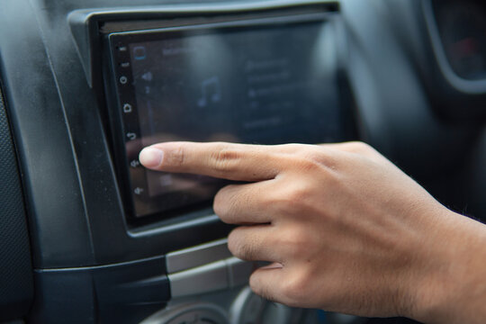 Finger turn up the volume on a car radio system. Transportation concept.