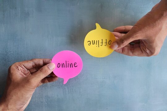 Top view image of hand holding speech bubble with text ONLINE and OFFLINE.