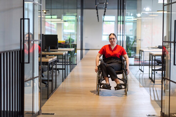 A modern young businesswoman in a wheelchair is surrounded by an inclusive workspace with...