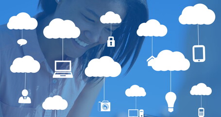 Image of clouds with electronic devices over caucasian woman using smartphone