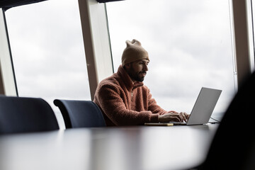 Man in Beanie Working on Laptop in Modern Office Space