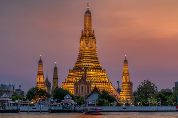 Wat Arun stupa, a significant landmark of Bangkok, Thailand, stands prominently along the Chao Phraya River, with a beautiful twilight.