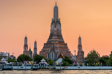 Wat Arun stupa, a significant landmark of Bangkok, Thailand, stands prominently along the Chao Phraya River, with a beautiful sunset sky. - 785191503