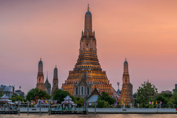 Wat Arun stupa, a significant landmark of Bangkok, Thailand, stands prominently along the Chao Phraya River, with a beautiful twilight. - 785191518
