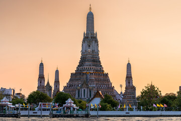 Wat Arun stupa, a significant landmark of Bangkok, Thailand, stands prominently along the Chao Phraya River, with a beautiful sunset sky. - 785191559