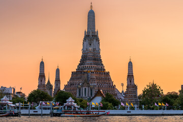 Wat Arun stupa, a significant landmark of Bangkok, Thailand, stands prominently along the Chao Phraya River, with a beautiful sunset sky. - 785191560