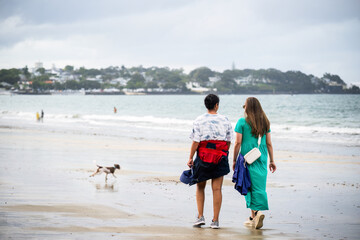 Women walking the dog on the beach. Unrecognizable people playing in the water. Takapuna Beach. Auckland. - 785191988