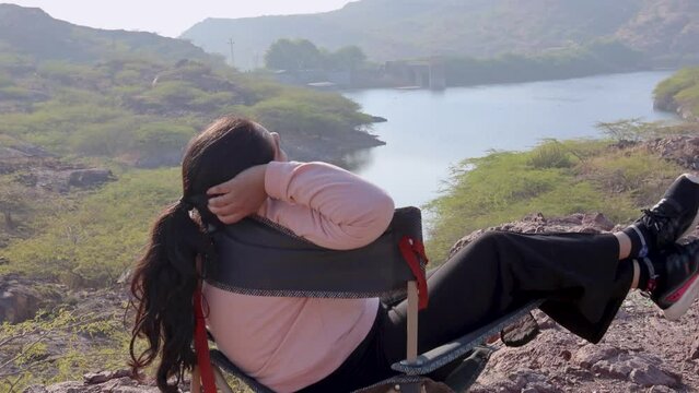 isolated girl relaxing at camping chair at mountain top with lake view at morning