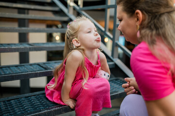 Mother holds and have fun her child with hearing aids and cochlear implants summer outdoor . Deaf and health concept. Diversity and inclusion.