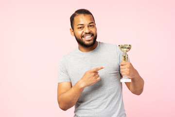 Overjoy smiling african american man wearing gray casual t shirt holding trophy cup