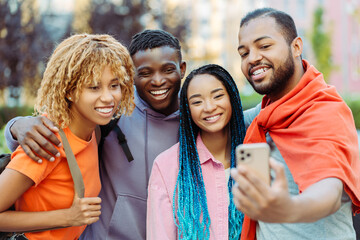 Group of smiling friends holding mobile phone, making selfie, shopping online together