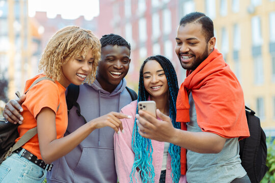 Group of smiling African American friends holding mobile phone, communication