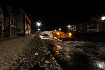A bridge over a river with a city in the background. Ochagavia, Navarre, Spain