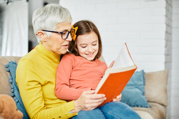 grandchild family child grandparent grandmother book reading elderly granddaughter girl  happy together read learning education woman