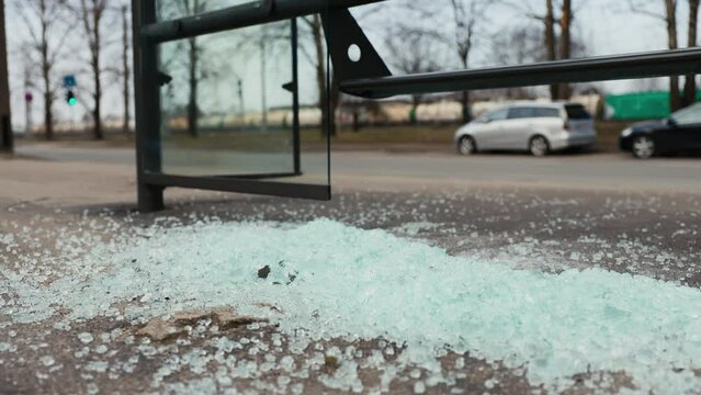 Illustrate the blight of urban vandalism as shattered glass remnants mark the damaged bus station, reflecting the darker side of city life
