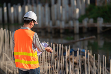 Construction engineer working on a bridge construction site over a river,Civil engineer supervising work,Foreman inspects work at a construction site
