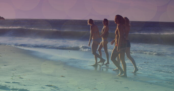Image of glowing lights over group of diverse female friends by the sea