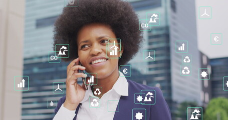 Image of ecology icons over african american businesswoman talking on smartphone