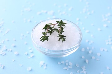 Salt and thyme in bowl on light blue background, closeup