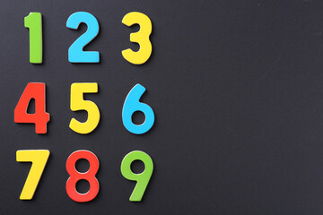 Colorful numbers on black background, flat lay. Space for text