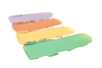 Samples of different color correcting concealers on white background, closeup