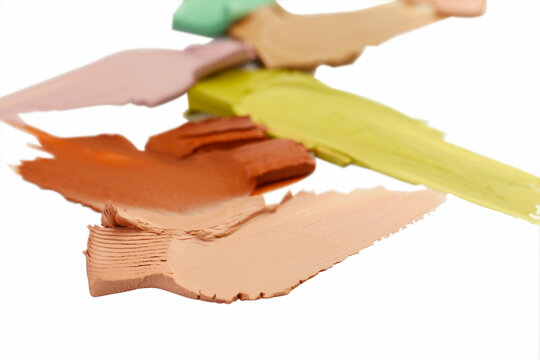 Samples of different color correcting concealers on white background, closeup