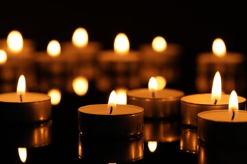 Burning candles on surface in darkness, closeup - obrazy, fototapety, plakaty