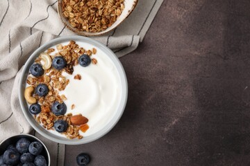 Bowl with yogurt, blueberries and granola on grey table, top view. Space for text