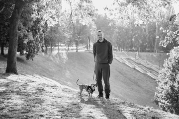 man with his cute puppy in a sweater in the park training, feeding, smiling. Spring, summer, autumn...