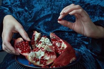 Female hand holds a pomegranate seed. Close-up shot with rich colors and textures. Healthy eating...