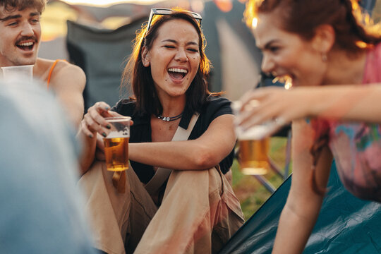 Happy friends laughing and having a good time over beers at a festival camp