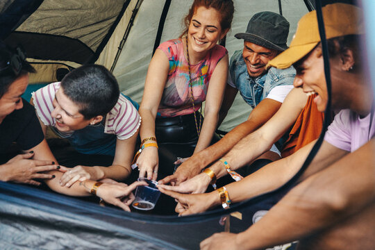 Group of friends playing a fun drinking game in a festival tent