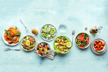 Fresh salads, overhead flat lay shot of an assortment. Variety of plates and bowls with green vegetables. Healthy food, top shot, with copy space