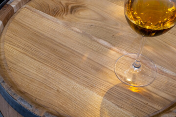 Wine glass with wine on wooden oak barrel. Lid of oak barrel close-up. View from above