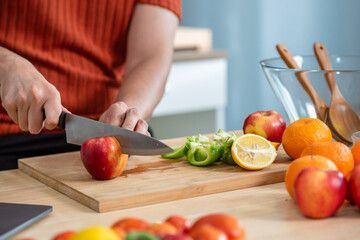 Hand chef knife cut and slice fresh Vegetables baby cos salad on wood board table .Make Salad Organic Vegetables mix lunch with green vegetables and fruit at kitchen table on wood cutting board.