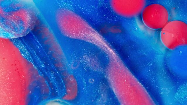 Glittering red and blue liquid ink fluid mixed together, abstract art.