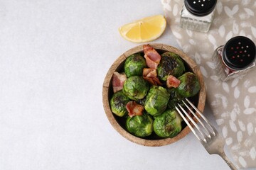 Delicious roasted Brussels sprouts and bacon served on light table, top view. Space for text
