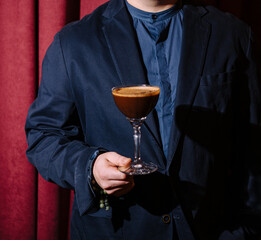 Man in suit holding espresso martini cocktail