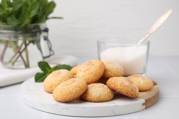 Tasty sweet sugar cookies, milk and mint on white tiled table, closeup