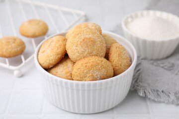 Tasty sugar cookies in bowl on white tiled table, closeup