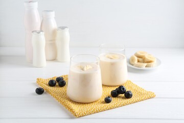 Tasty yogurt, banana and blueberries on white wooden table