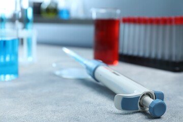 Laboratory analysis. Micropipette on light grey table, closeup. Space for text